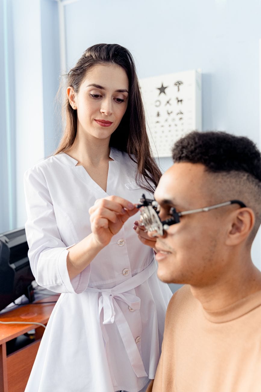An optometrist adjusting a trial frame on a patient