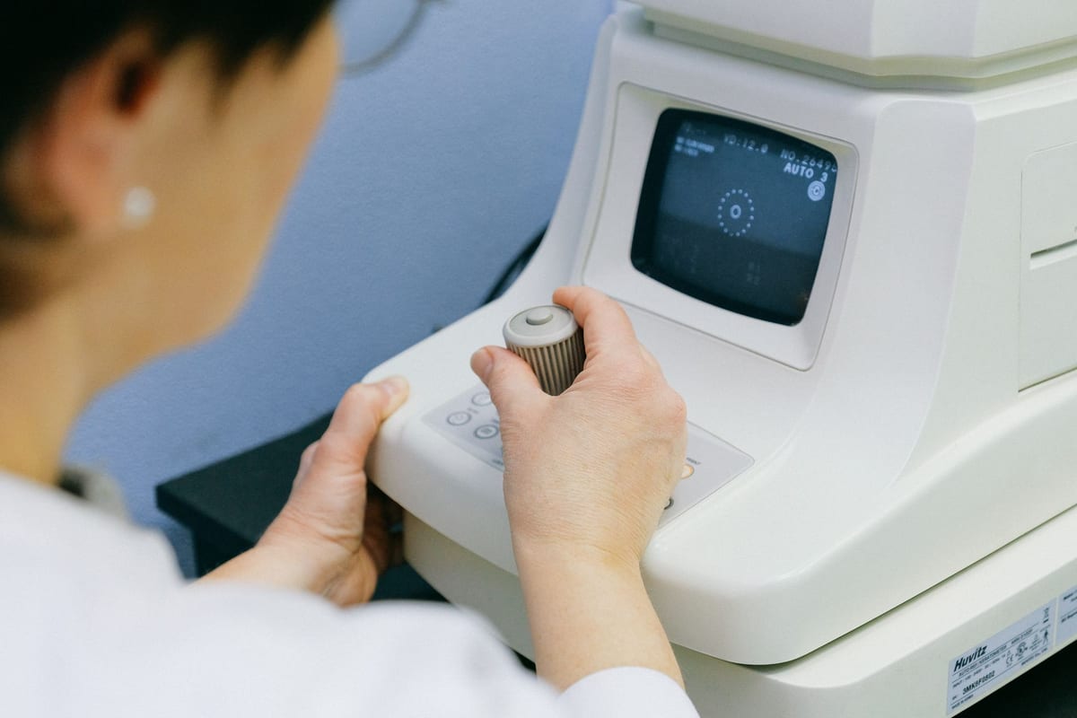 An optometrist operating an auto-refractor during an eye exam